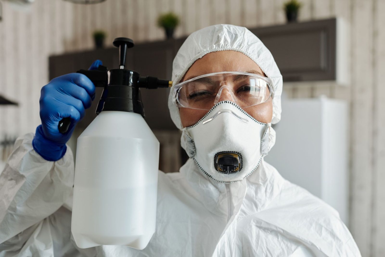 Pest control technician in a mask with a sprayer