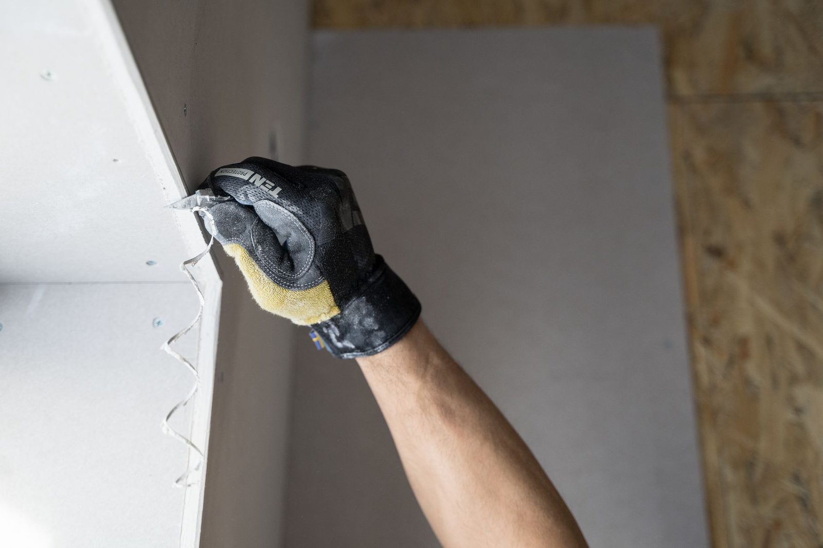 Gloved hand sealing a gap in a wall
